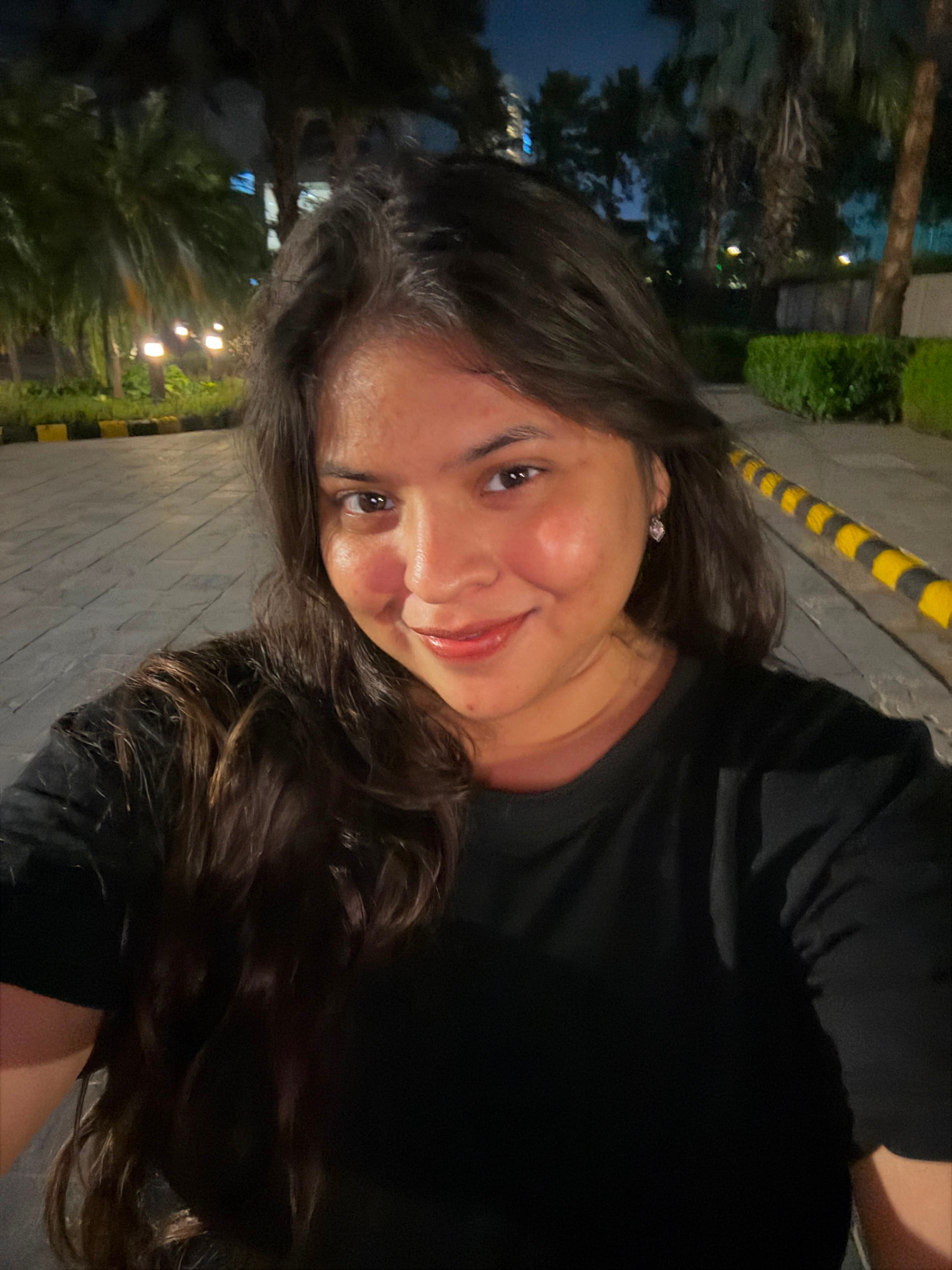 Sneha Rani smiling at the camera, outdoors in the evening